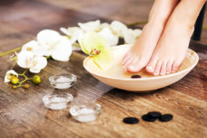 Spa concept of foot pedicure in bowl with orchids and river stones